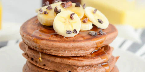 Healthy chocolate pancakes with banana and syrup, high protein breakfast option
