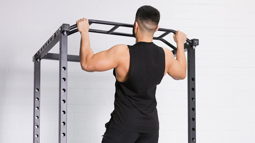 Man performing pull ups on power rack for back and upper body strength training