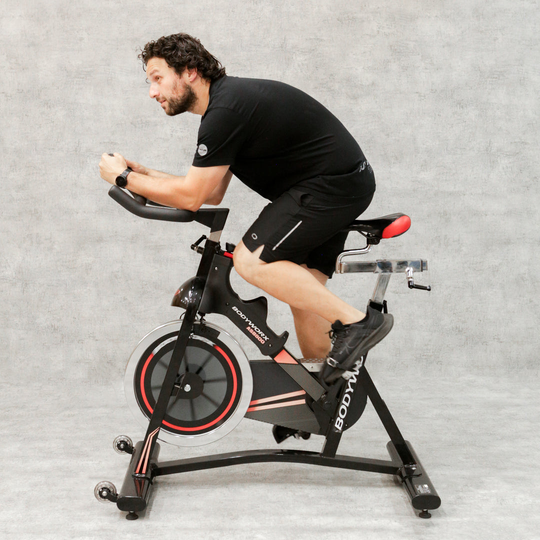 Man in black tshirt riding red and black spin bike