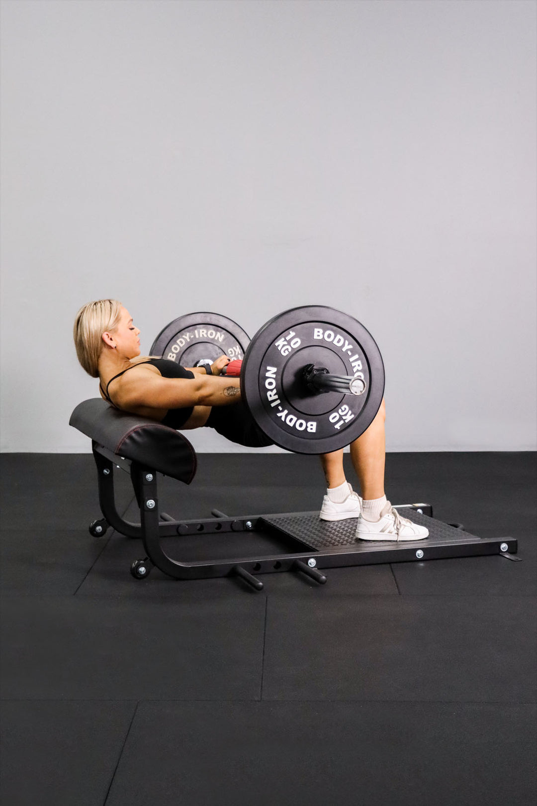 Female using with barbell on Body Iron hip thrust platform