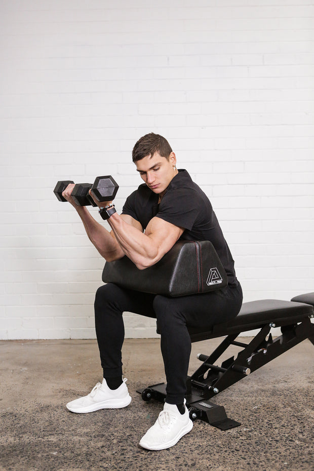 Man using multi pad to performer seated dumbbell preacher curls
